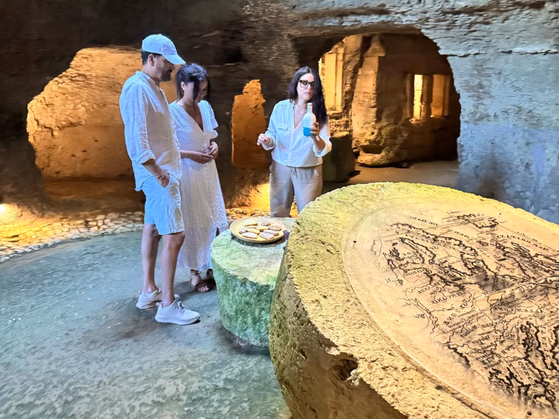Visitors enjoy a guided olive oil tasting in a historic underground mill near Otranto, surrounded by ancient stone walls.