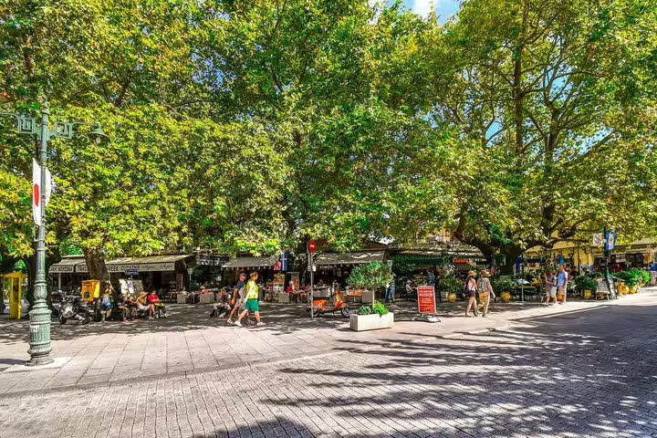 Lively Olympia village square with cafes under plane trees, relaxing break on Olympia full day tour