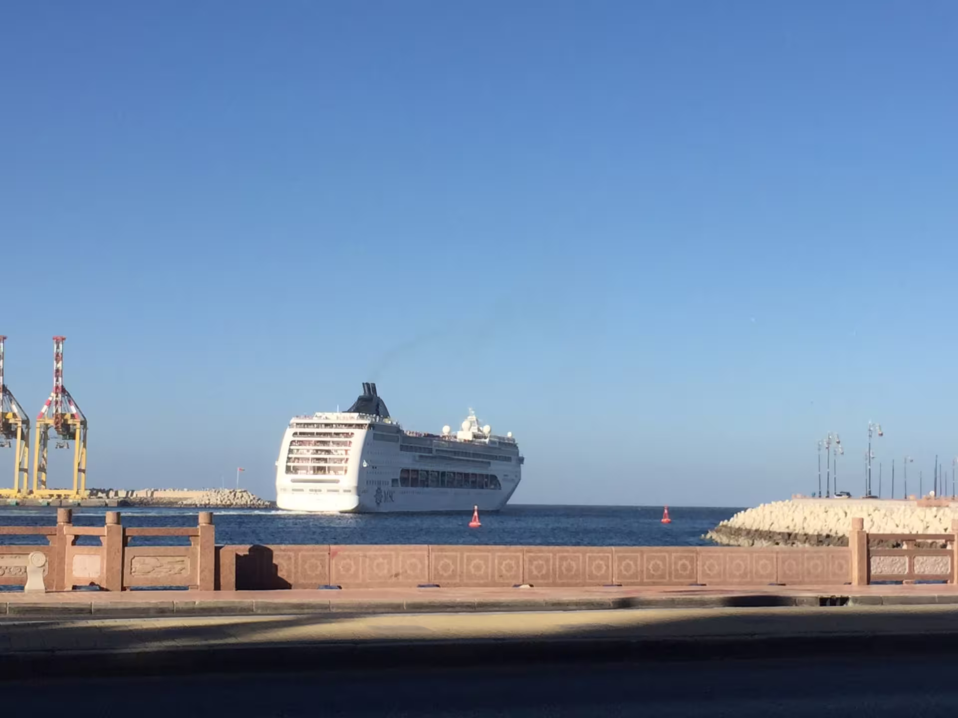 Cruise ship departing Oman's port under a clear blue sky, highlighting travel and maritime tourism opportunities.
