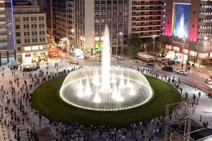 Evening view of Omonia Square fountain in Athens, a city highlight on a private full-day Corinth tour