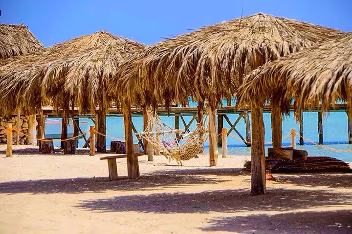 Thatched umbrellas and hammocks on Orange Bay Giftun Island beach, Hurghada snorkeling tour relaxation