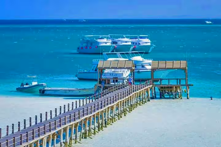 Orange Bay Giftun Island pier with boats in turquoise Red Sea, Hurghada snorkeling day trip transfer