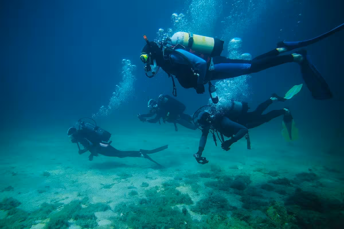 Group scuba diving over sandy seabed in the Red Sea near Orange Bay Island, Hurghada, Egypt day trip
