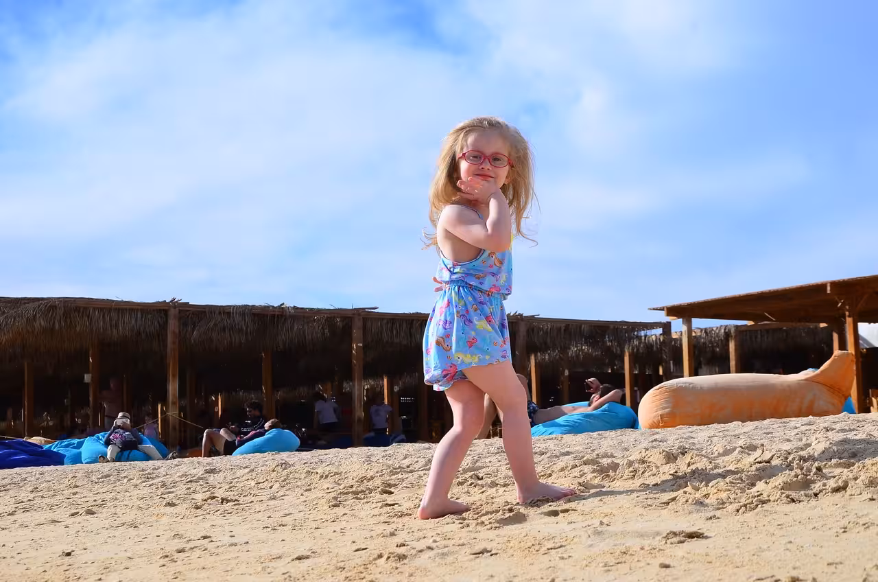 Child playing on sandy Orange Bay Island beach near shaded huts, family-friendly snorkeling trip with lunch