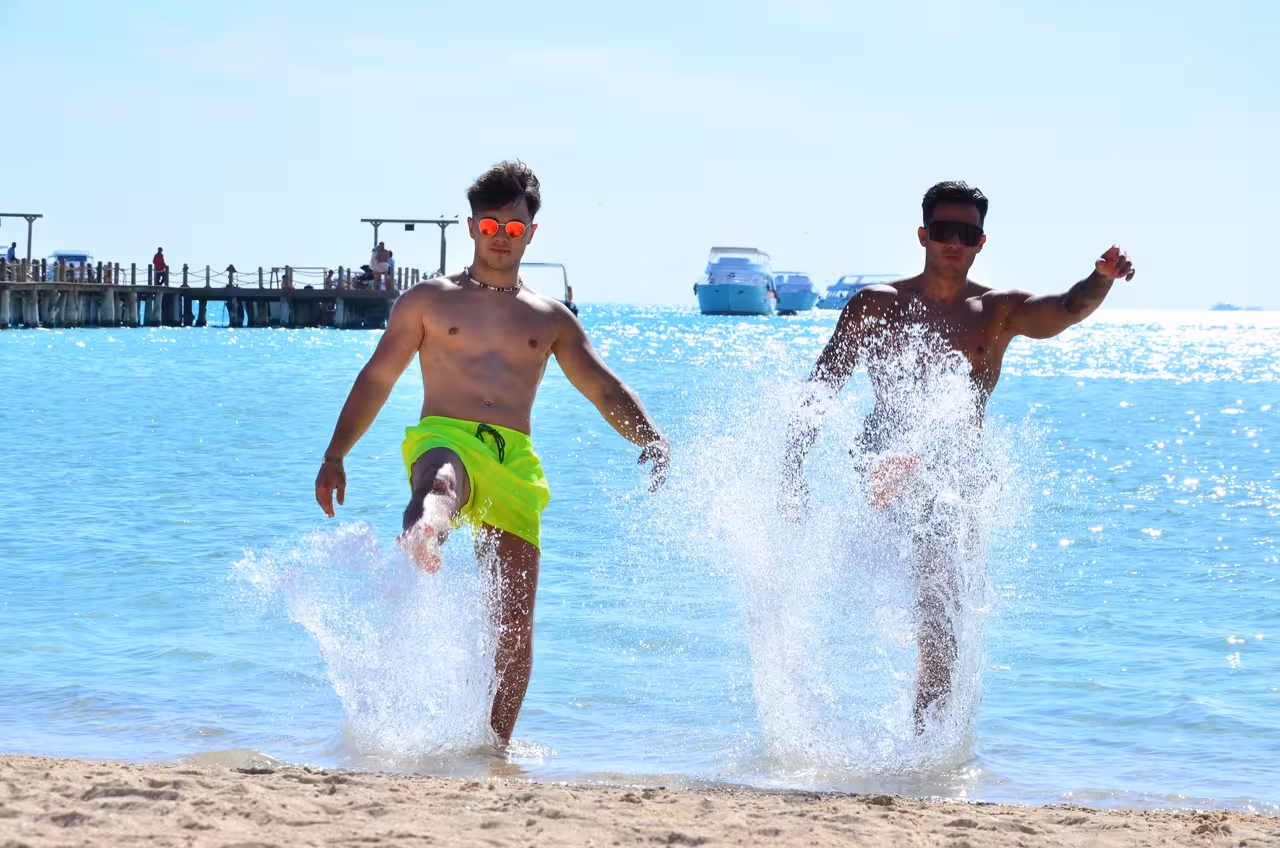 Friends splashing in shallow turquoise water at Orange Bay Island, Hurghada snorkeling excursion with lunch included