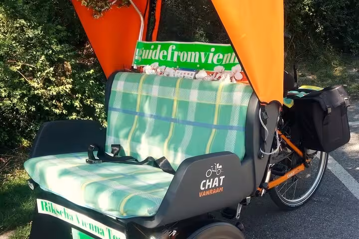 Orange electric rickshaw with green plaid bench on Vienna private tour route, eco-friendly city ride