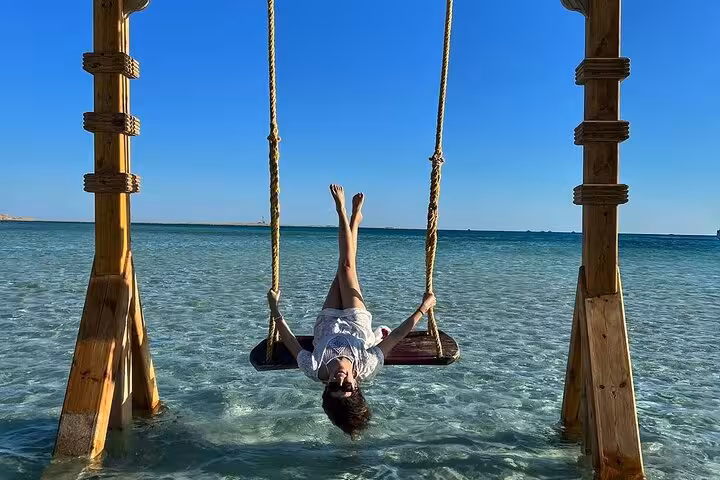 Wooden swing over crystal-clear Red Sea at Orange Bay, Giftun Island, part of Hurghada snorkeling lunch tour