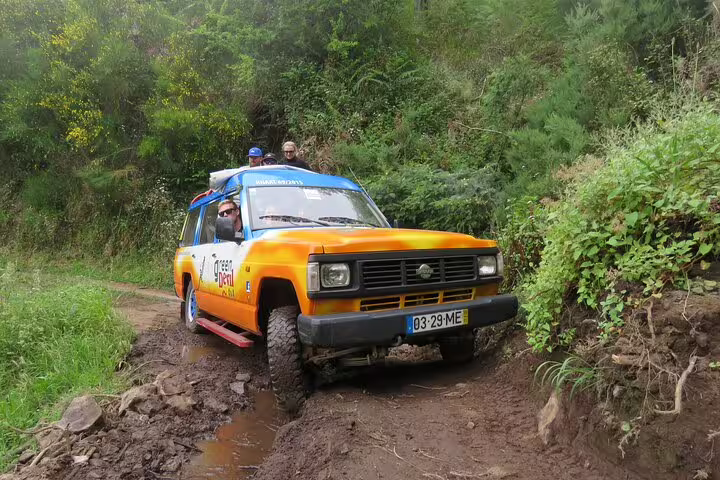 Orange off-road vehicle navigating a rugged trail in Madeira's lush landscape, perfect for adventure and wine tours.