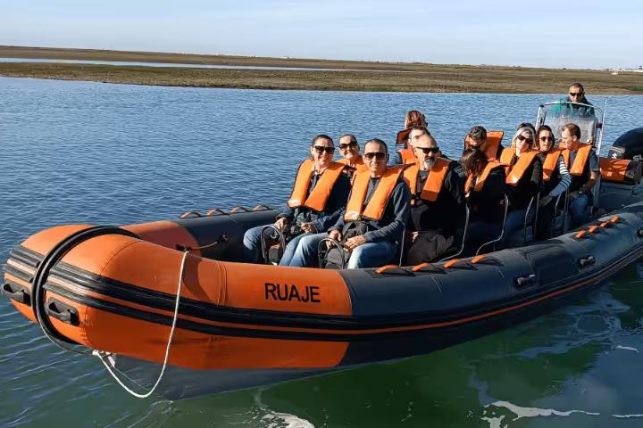 Orange RIB boat with passengers in life jackets on a Faro dolphin watching tour in the Algarve lagoon waters