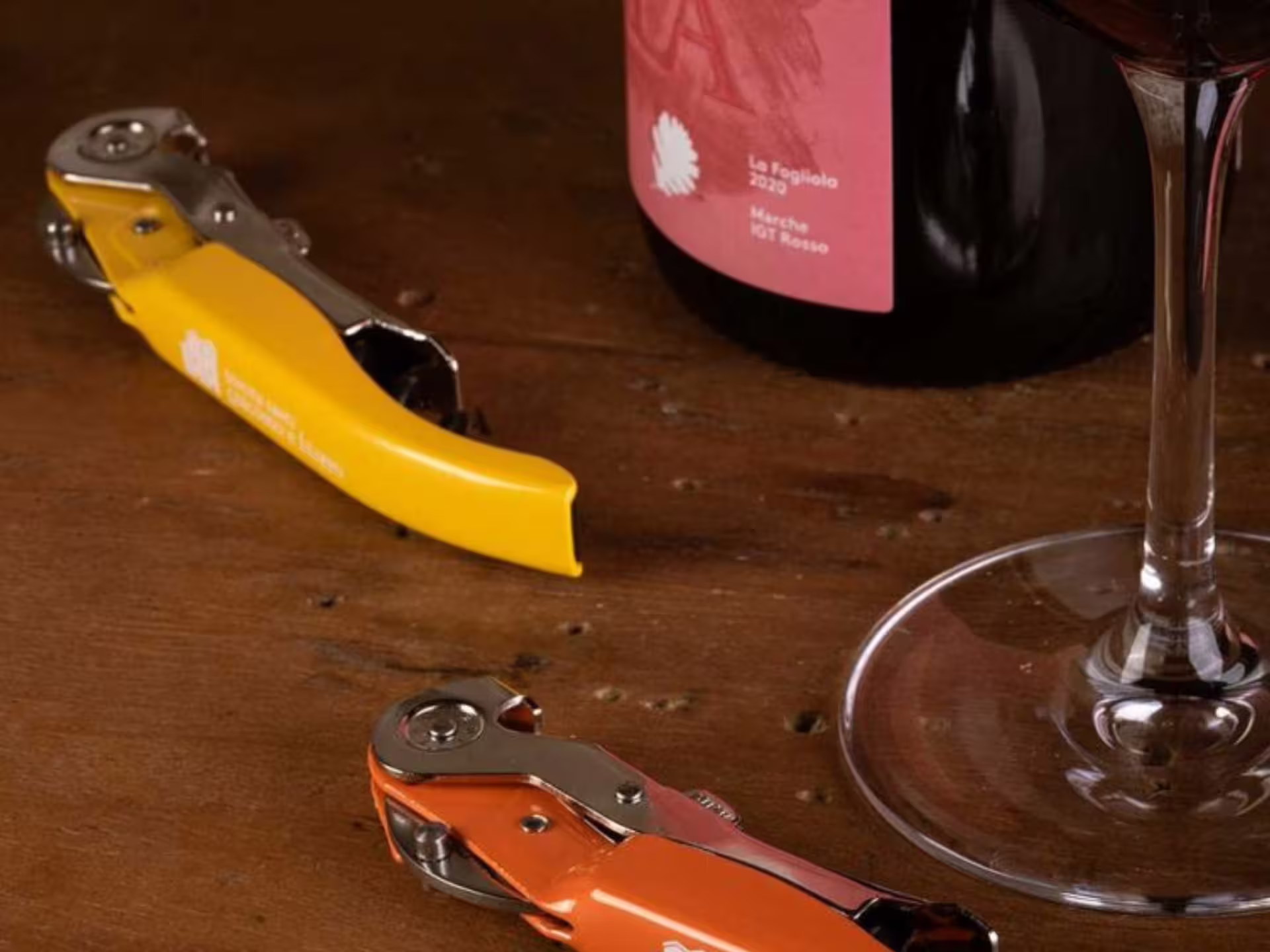 Organic Marche wine bottle with corkscrews and tasting glass on table, boutique winery visit near Urbino