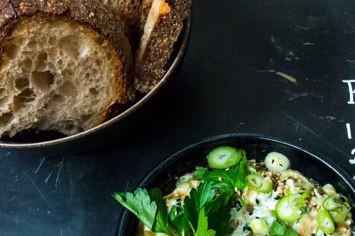 Artisanal bread with a gourmet dish garnished with fresh herbs, perfect for an organic wine tasting and food pairing experience.