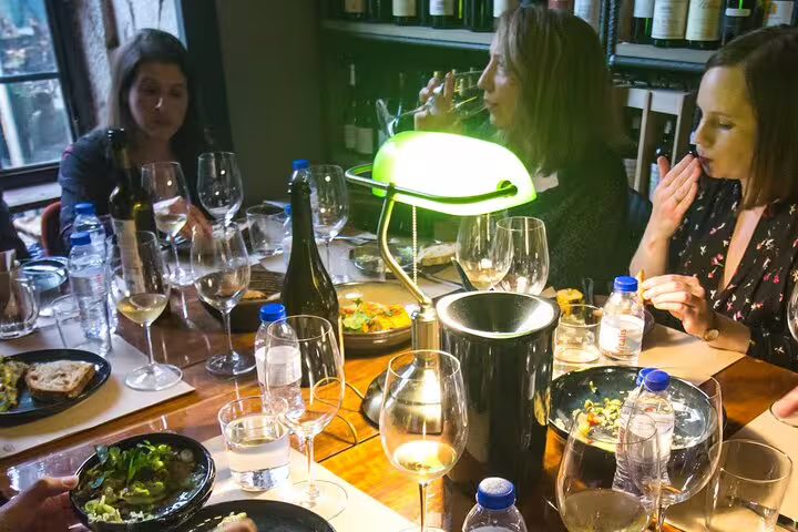 People enjoying a natural and organic wine tasting and food pairing, featuring diverse wines and gourmet dishes in an intimate setting.