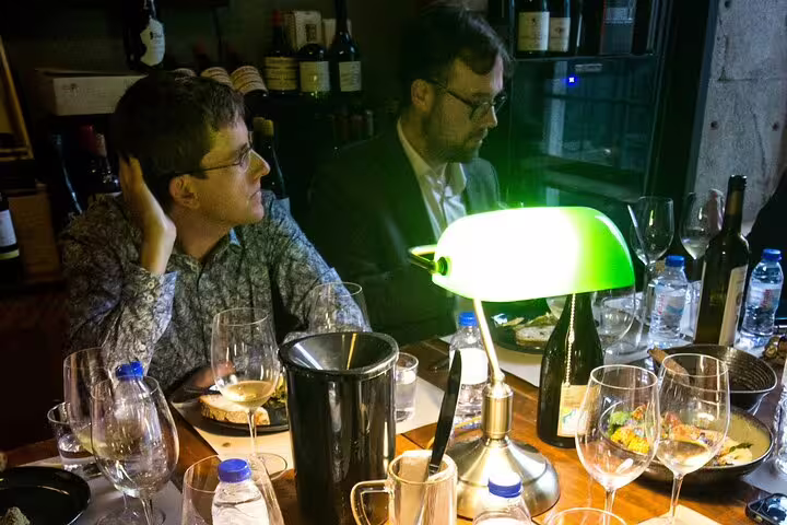 Guests enjoying a natural and organic wine tasting with gourmet food pairing at a cozy, ambient-lit dining table.