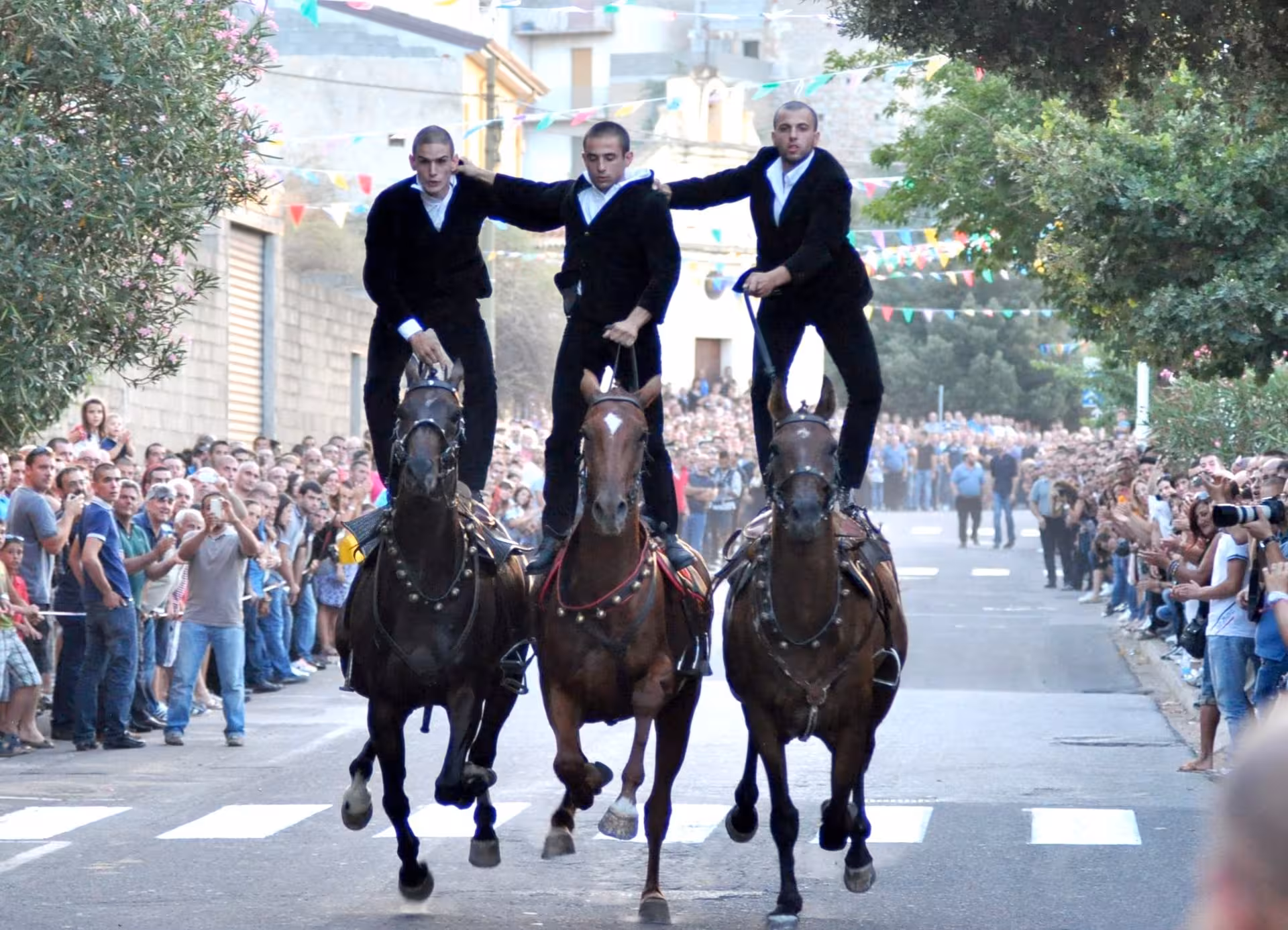 Traditional horse riders perform daring stunts at a vibrant Orgosolo street festival.