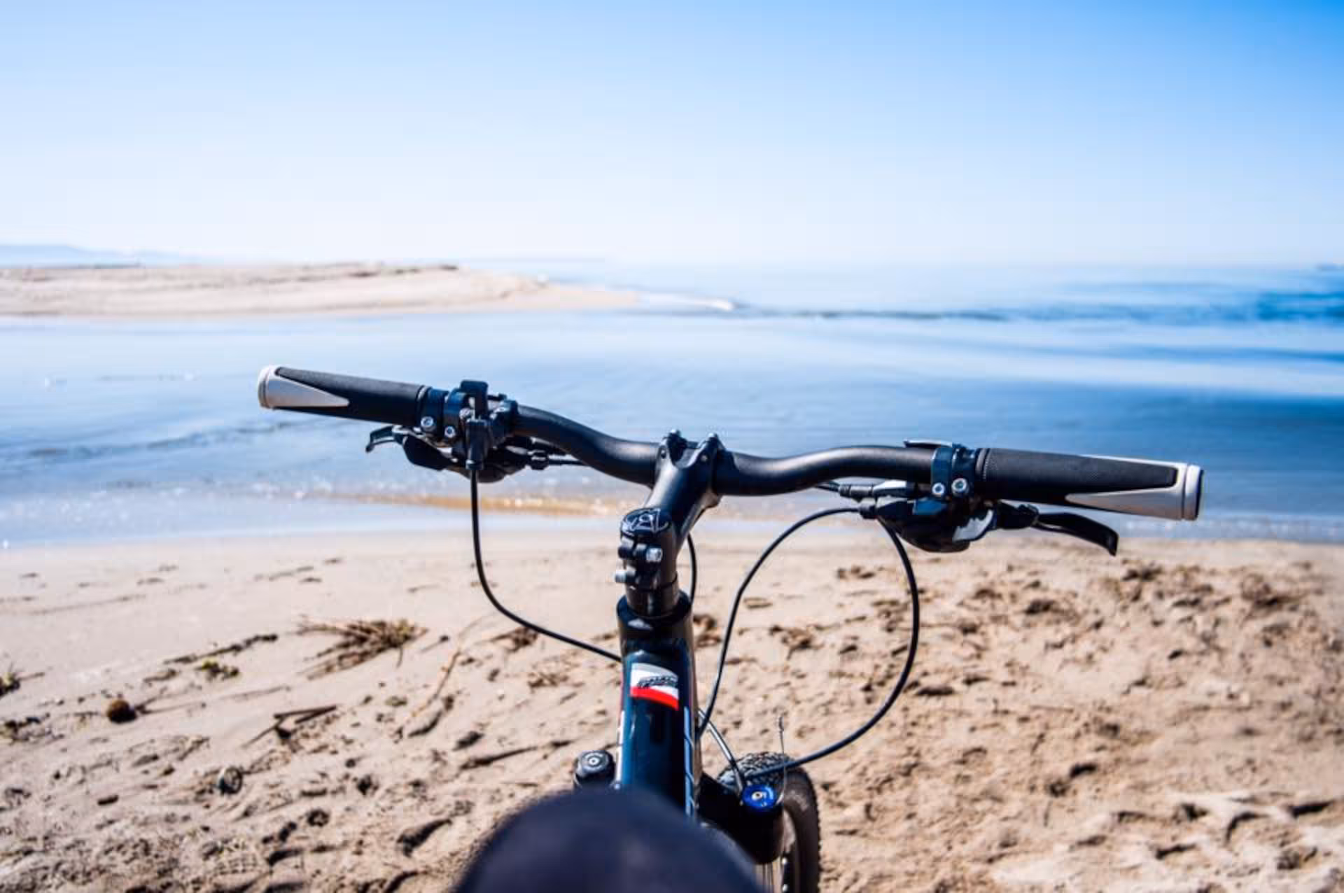 View from bike handlebars on sandy Torregrande beach, Oristano coast tour offers stunning seaside rides.