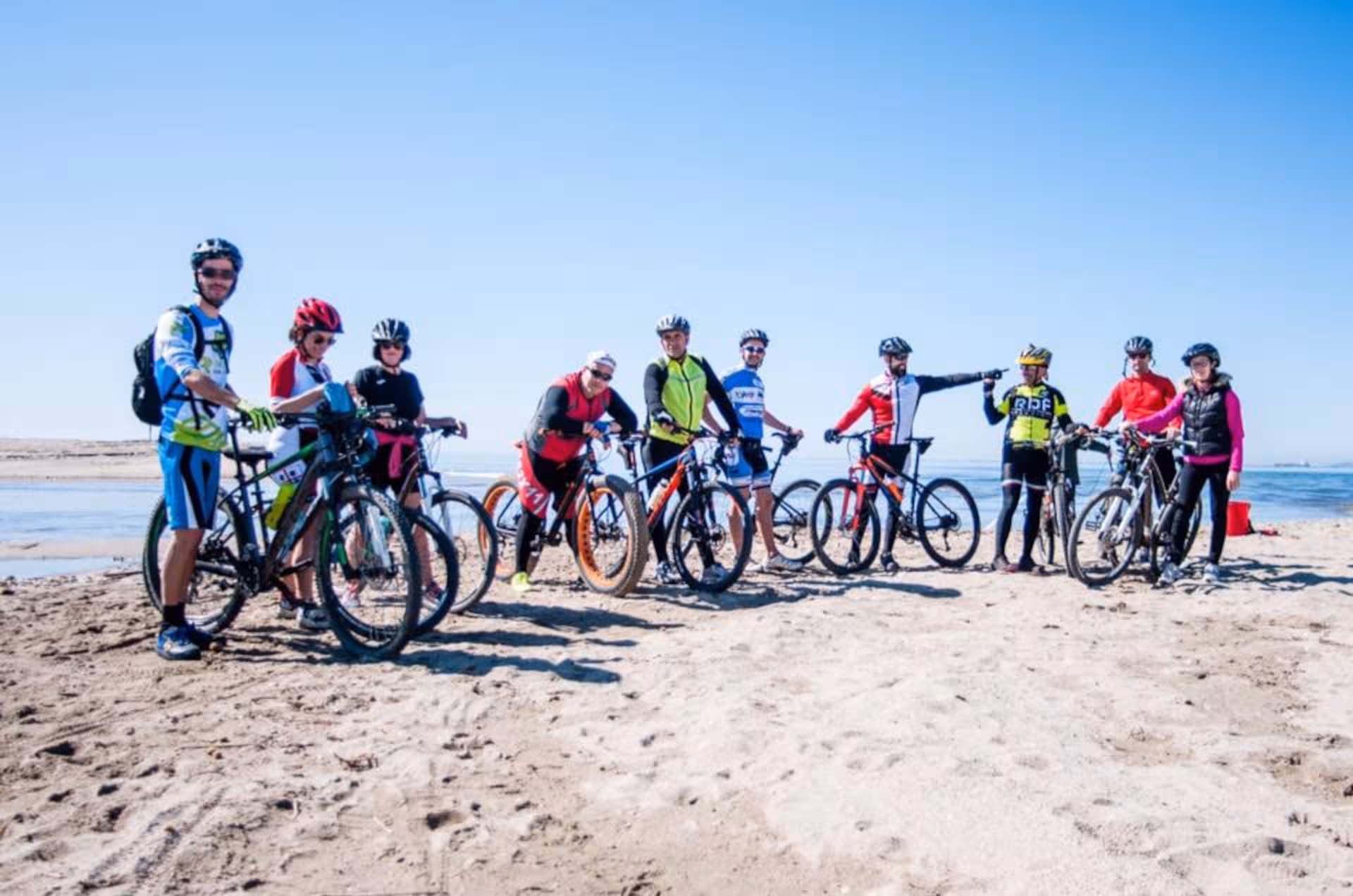 Group of cyclists enjoying a sunny ride along the Torregrande coast during an Oristano bike tour.
