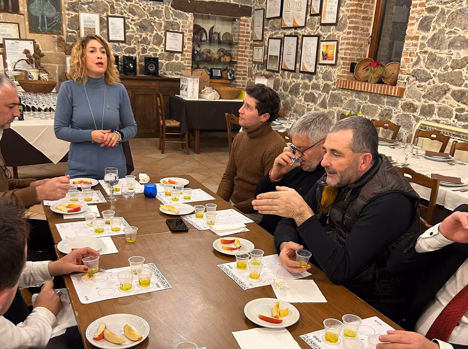 Group of people engaged in an olive oil tasting session at a rustic Oristano farm venue.