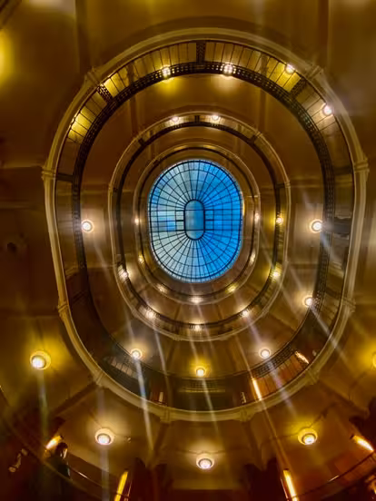 Stunning view of an ornate glass ceiling in a historic building, perfect for architecture tour enthusiasts.