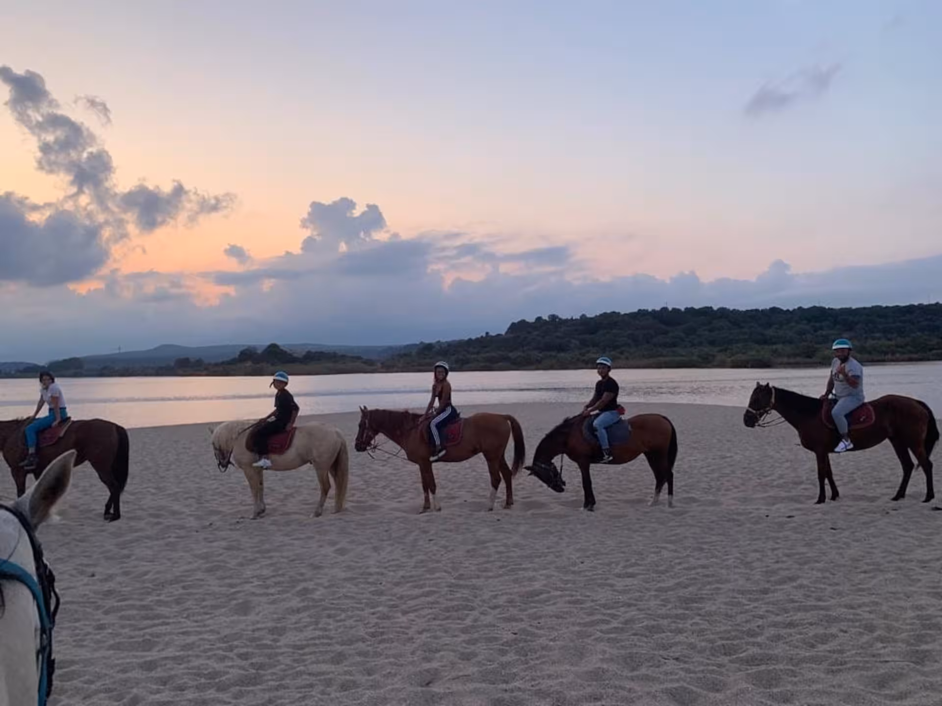 Group horseback riding on Orosei beach at sunrise, perfect for scenic coastal adventures.