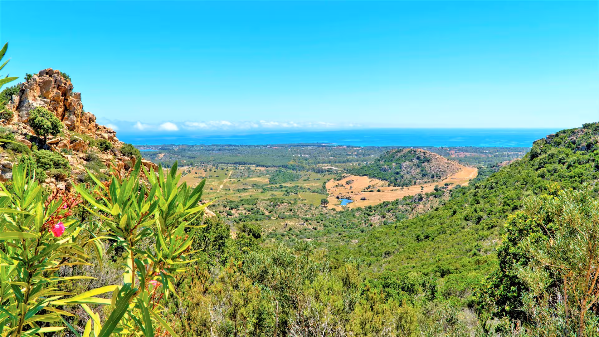 Panoramic view of lush valleys and distant sea on the Capo Comino jeep tour, showcasing Sardinia's natural beauty.