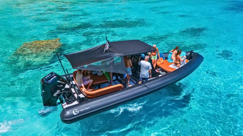 Travelers relax on a dinghy in the turquoise waters of Cala Luna, exploring the Sardinian coastline.