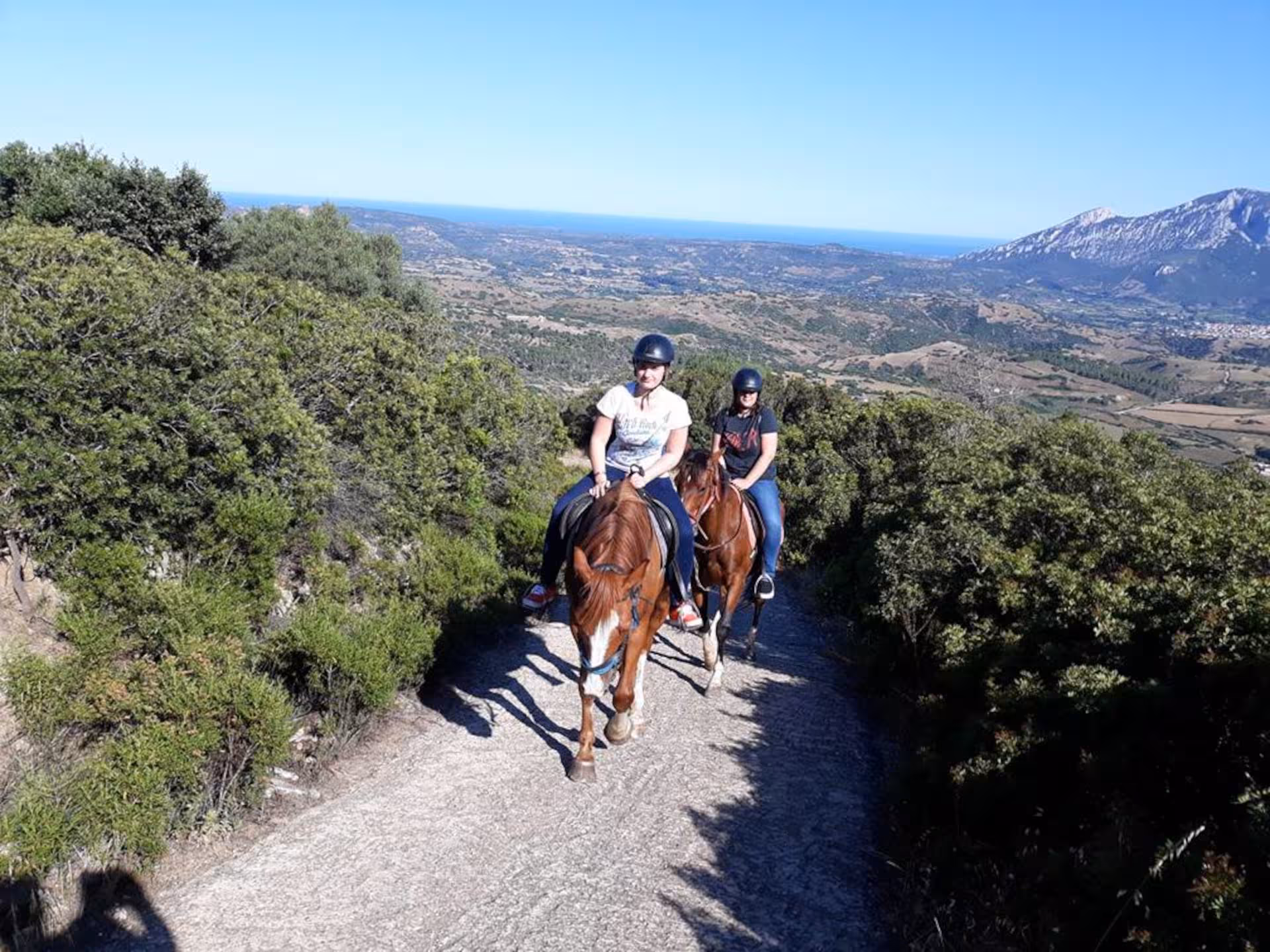 Riders on horseback with panoramic views of Irgoli's stunning landscapes and distant mountains in Orosei.