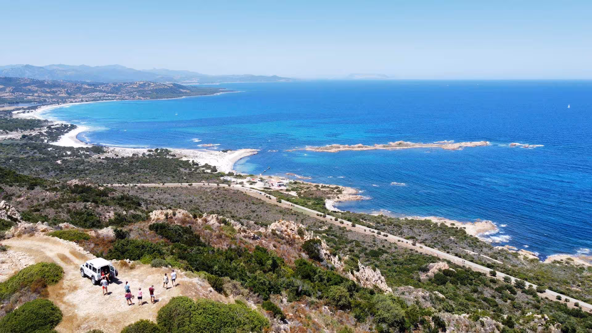 Aerial view of Capo Comino's stunning coastline with a Jeep tour group exploring the scenic landscape.