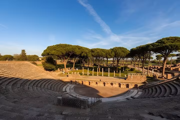 View of the ancient amphitheater surrounded by lush trees in Ostia Antica, ideal for historical exploration.