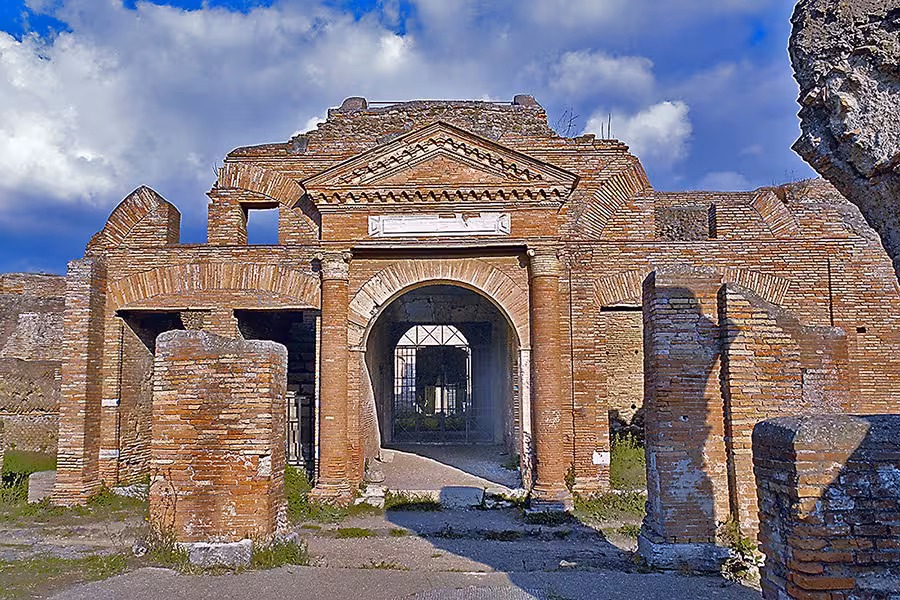 Marvel at the grand entrance of Ostia Antica's ancient ruins on a Fiat '500 vintage tour.