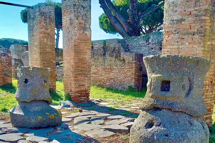 Weathered stone columns and millstones in Ostia Antica ruins explored on exclusive ancient river cruise and guided tour from Rome