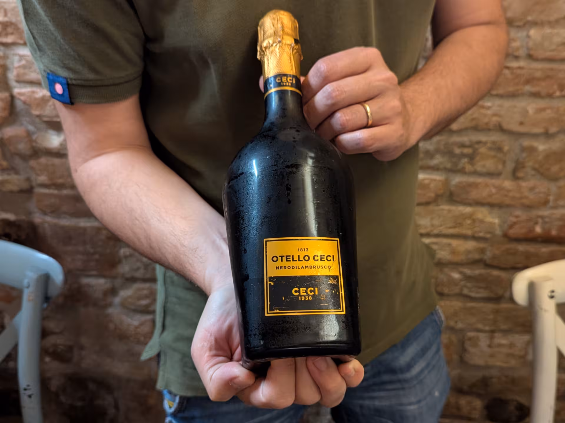 Hand holding a bottle of Otello Ceci Lambrusco wine, perfect for Parma's wine tasting experience.