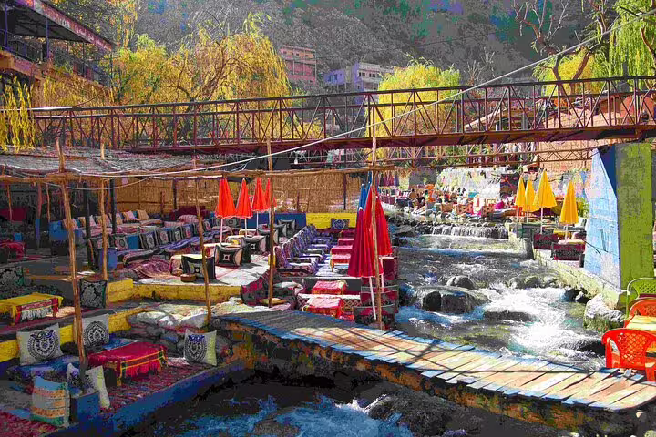 Riverside cafes along Ourika River under a footbridge in the Atlas Mountains, Marrakech to Ourika Valley tour