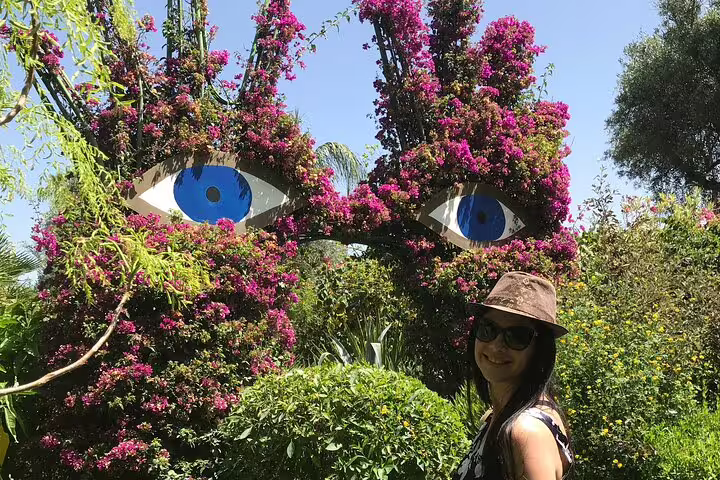 Traveler in hat at Ourika Valley garden with bougainvillea eye sculpture, Morocco day tour photo stop