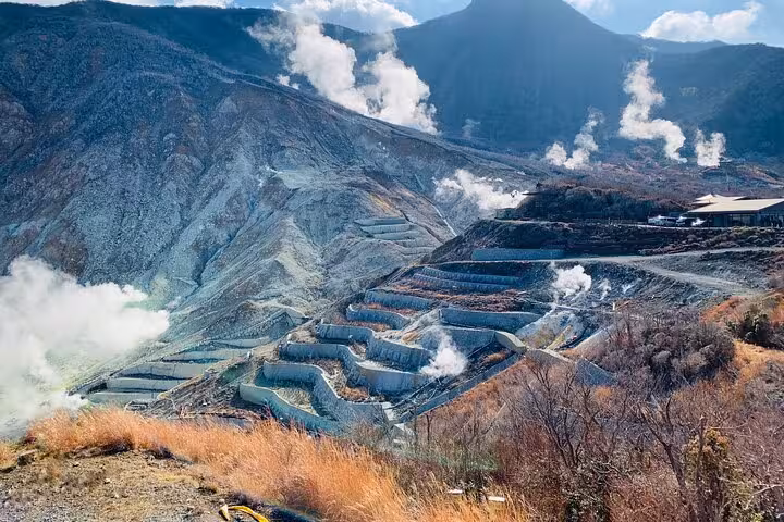 Scenic view of Owakudani Valley in Hakone with steaming vents and terraced landscape, perfect for Mt. Fuji tours.