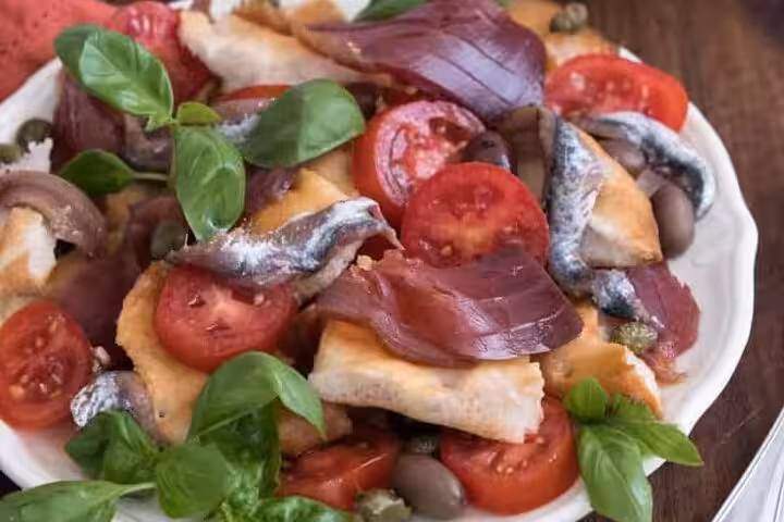A vibrant seafood platter featuring fresh anchovies, tomatoes, olives, and basil, perfect for a Riviera culinary adventure.