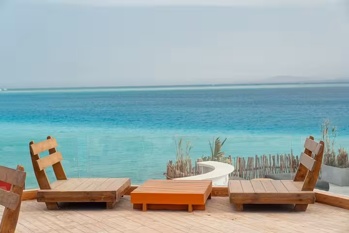 Wooden sun loungers facing turquoise Red Sea on Ozirea Island, relaxing stop on Hurghada speedboat tour