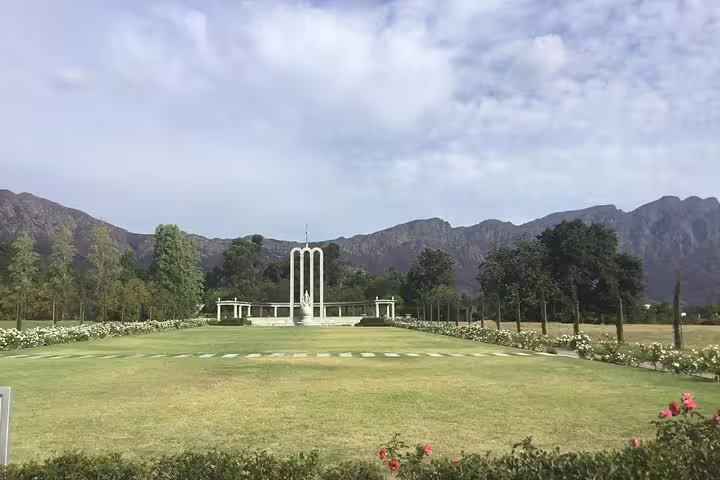 Sprawling green lawn with monument and mountain backdrop in Paarl wine tour.
