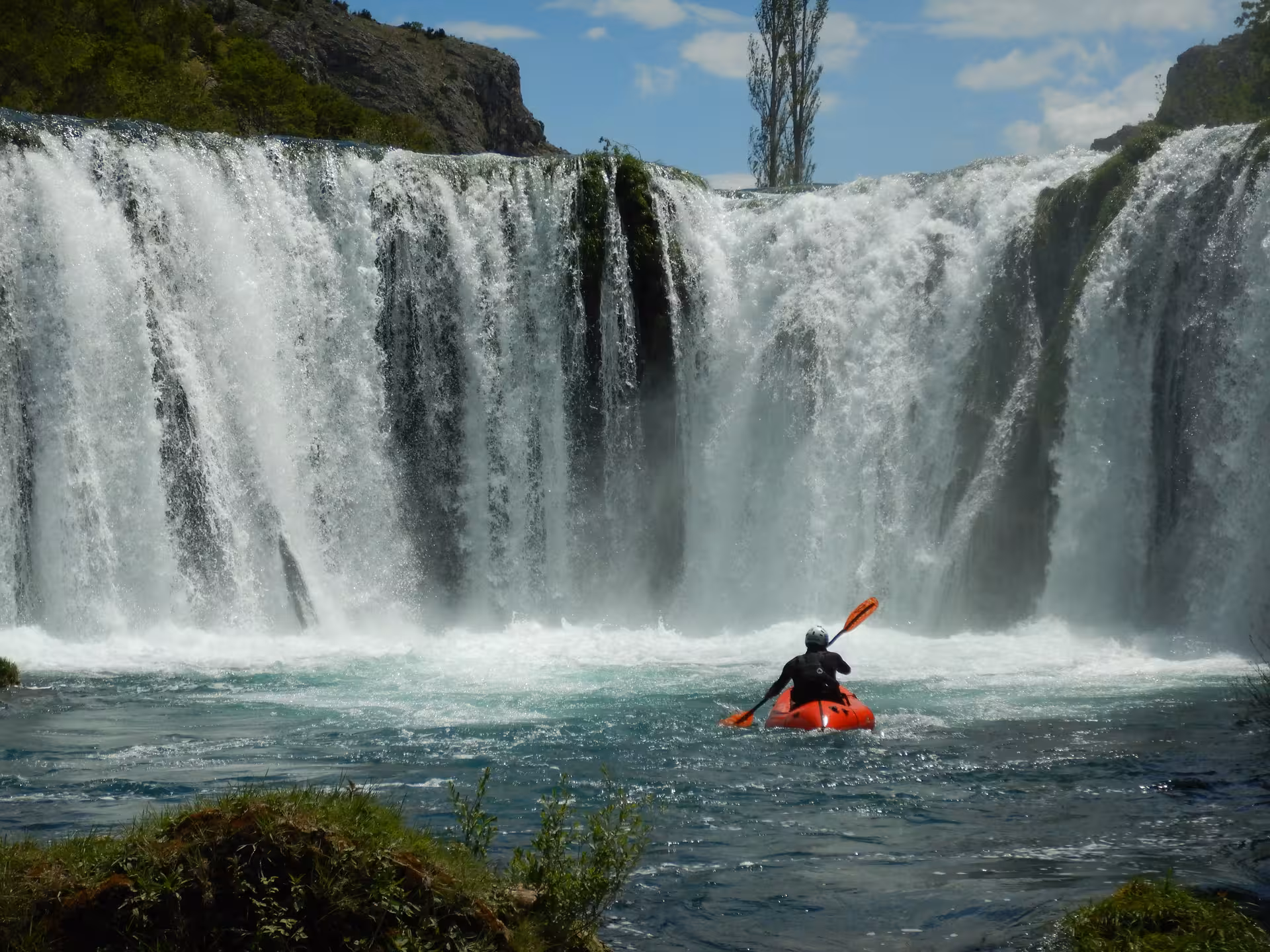 Solo packrafter approaching majestic waterfall on Zrmanja River, ideal for adventure seekers.