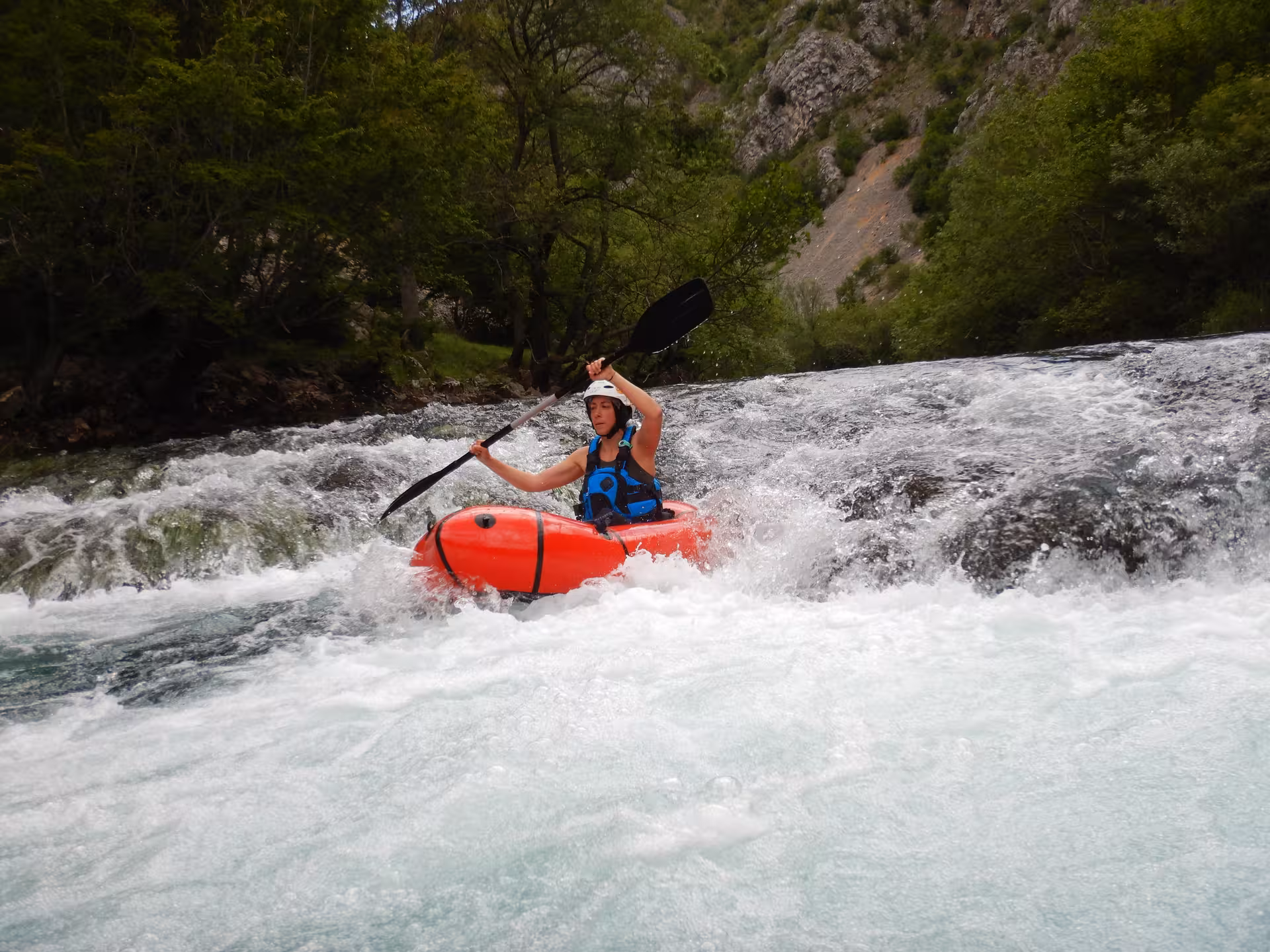 Thrilling packrafting experience on Zrmanja River's rapids, surrounded by rugged terrain and vibrant forest.