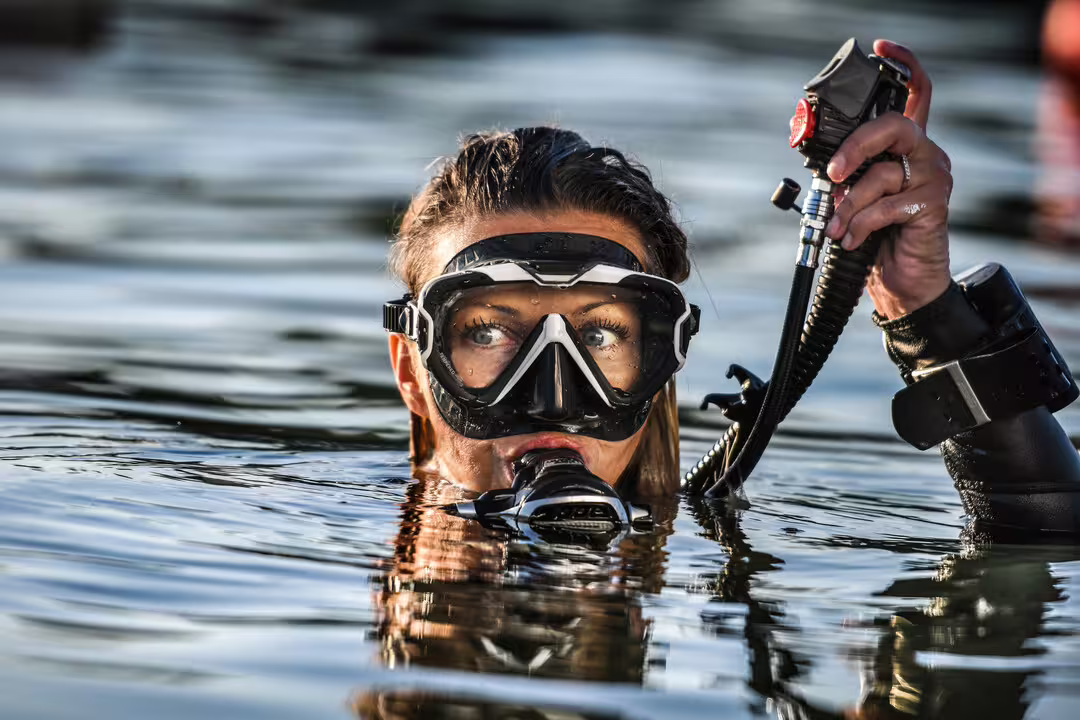 Diver in full gear prepares for an open water course, showcasing underwater skills and adventure training in clear waters.