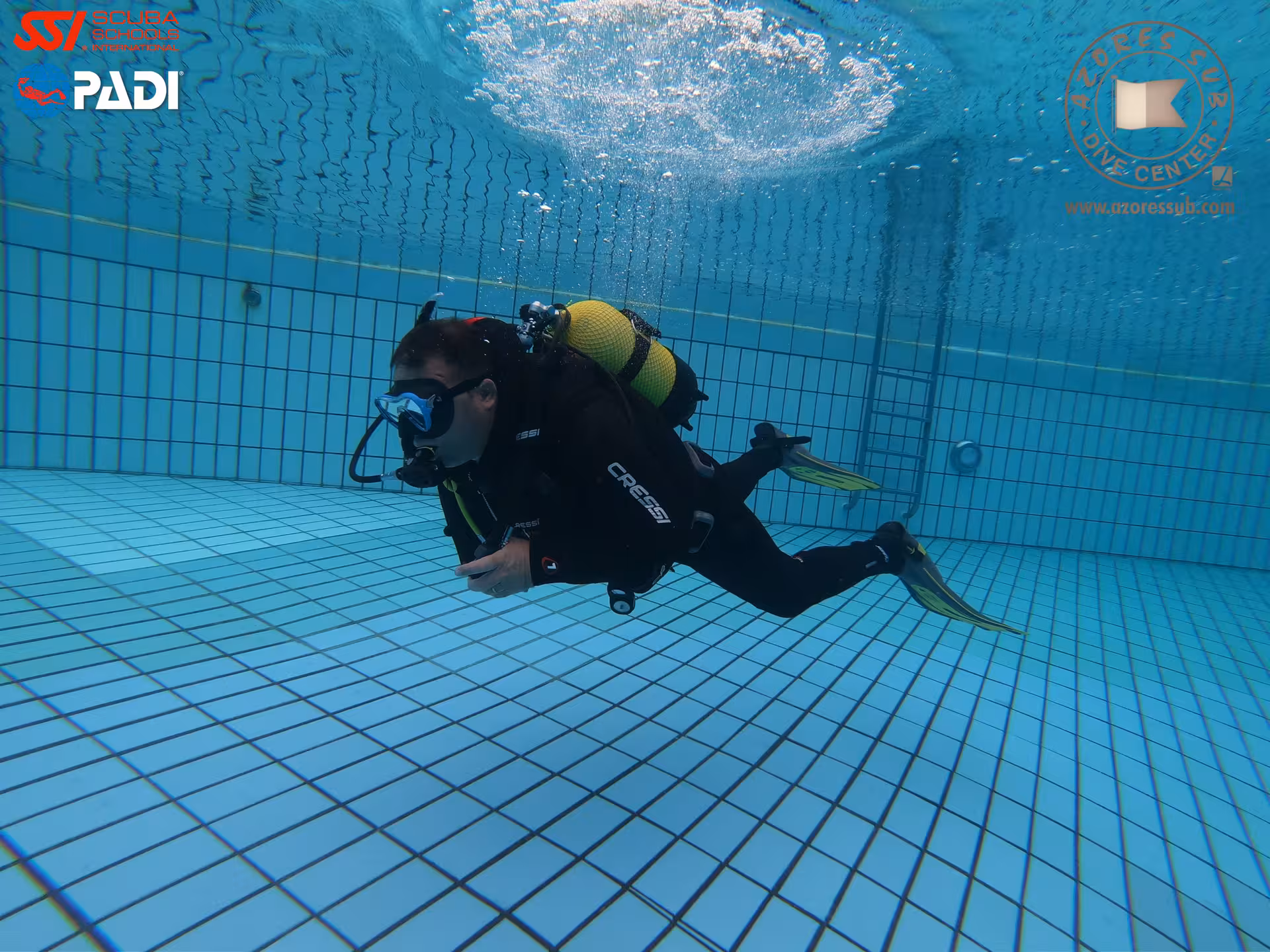 Scuba diver practicing PADI Perfect Buoyancy in a pool, neutral hover with fins up and steady breathing control