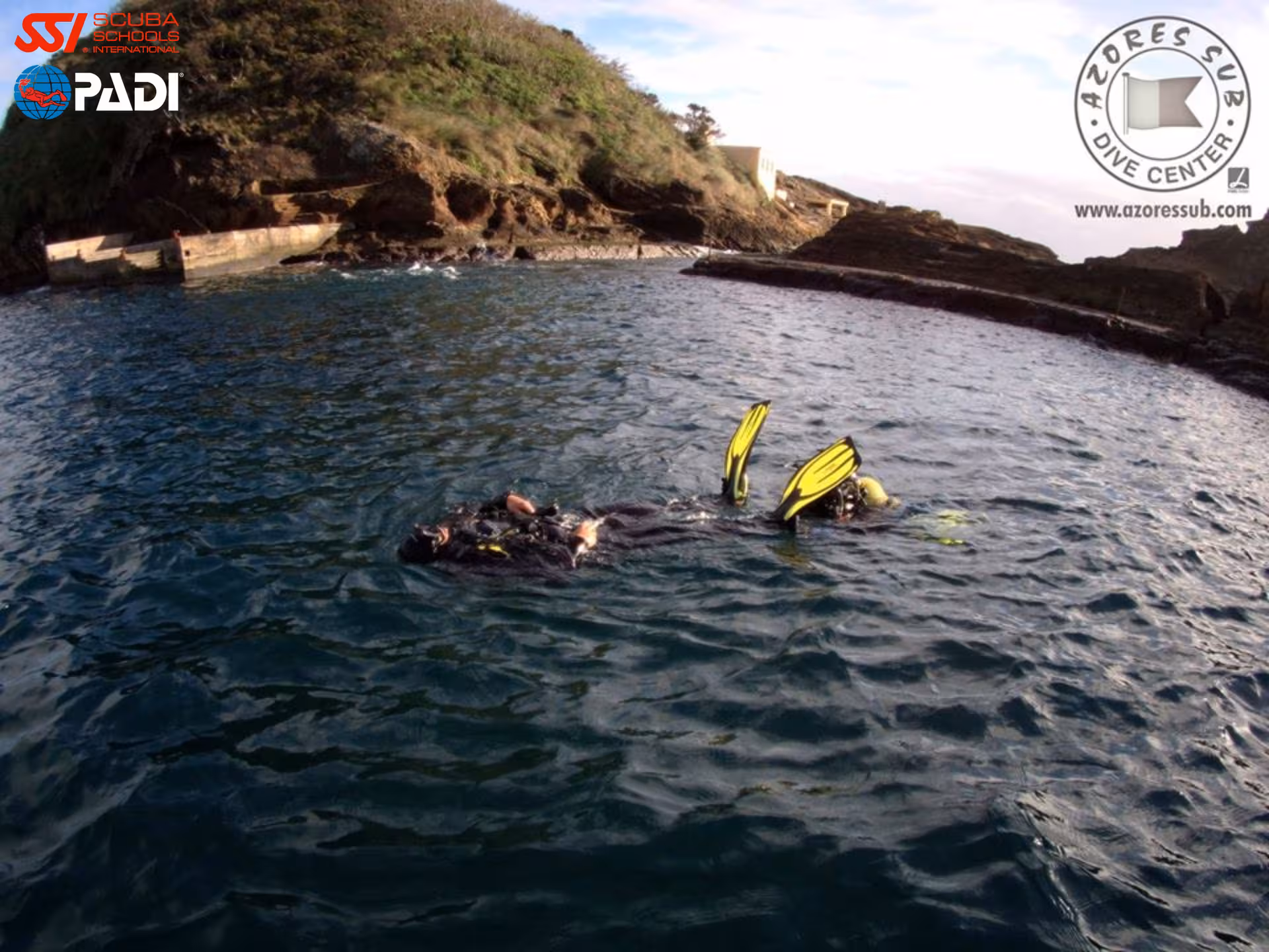 PADI Rescue Diver course drill with diver tow and yellow fins in sheltered Azores bay near cliffs