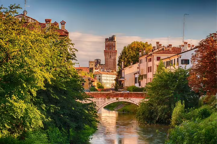 Padua highlights self-guided scavenger hunt along a canal with stone bridge and historic tower skyline