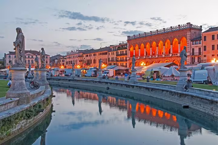Padua self-guided scavenger hunt at Prato della Valle canal, statues and lit Loggia at dusk