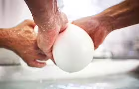 Hands shaping fresh buffalo mozzarella during an artisanal cheese-making demo on a Paestum farm tour with lunch