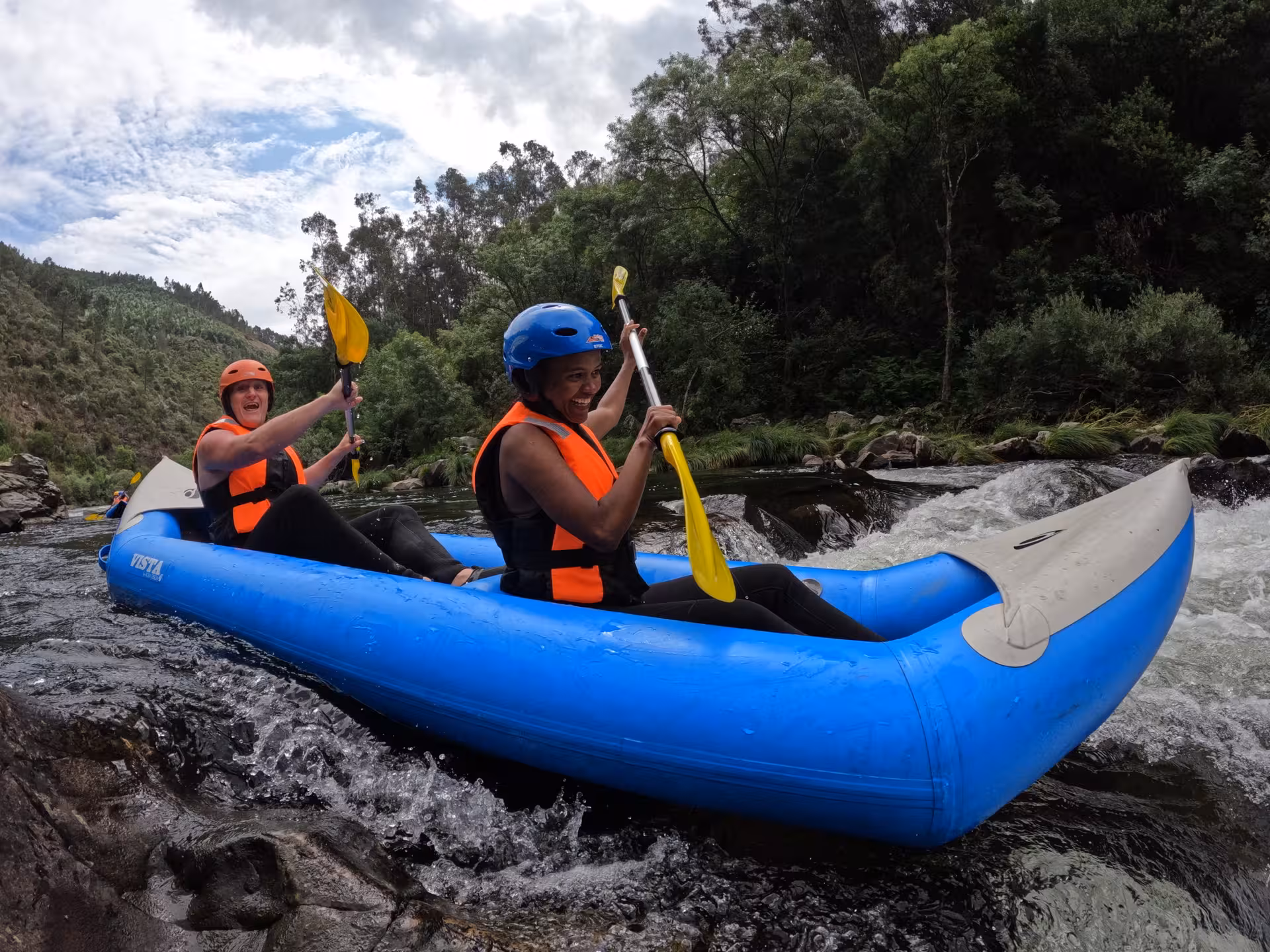 Smiling paddlers in inflatable canoe on Paiva River, Arouca, Portugal, guided whitewater rafting tour