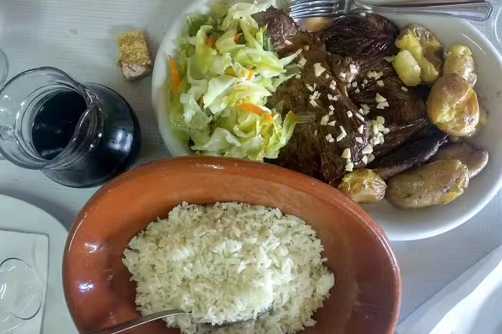 Traditional Portuguese meal with roasted meat, vegetables, and rice, paired with wine, featured in the Paiva Walkways tour.