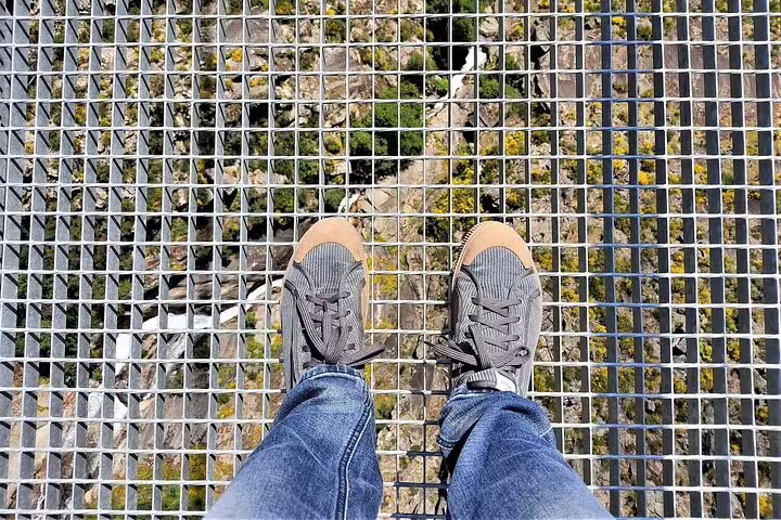 Walking on the thrilling Paiva Walkways suspension bridge with a scenic view of nature below, part of the Porto tour.