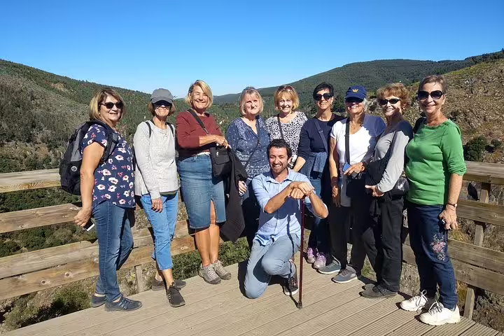 Group of tourists enjoying a sunny day on the scenic Paiva Walkways with stunning views of the Portuguese countryside.