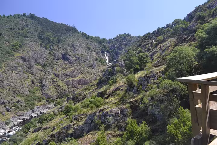 Scenic Paiva Walkways view with a cascading waterfall amid rugged cliffs and lush greenery.
